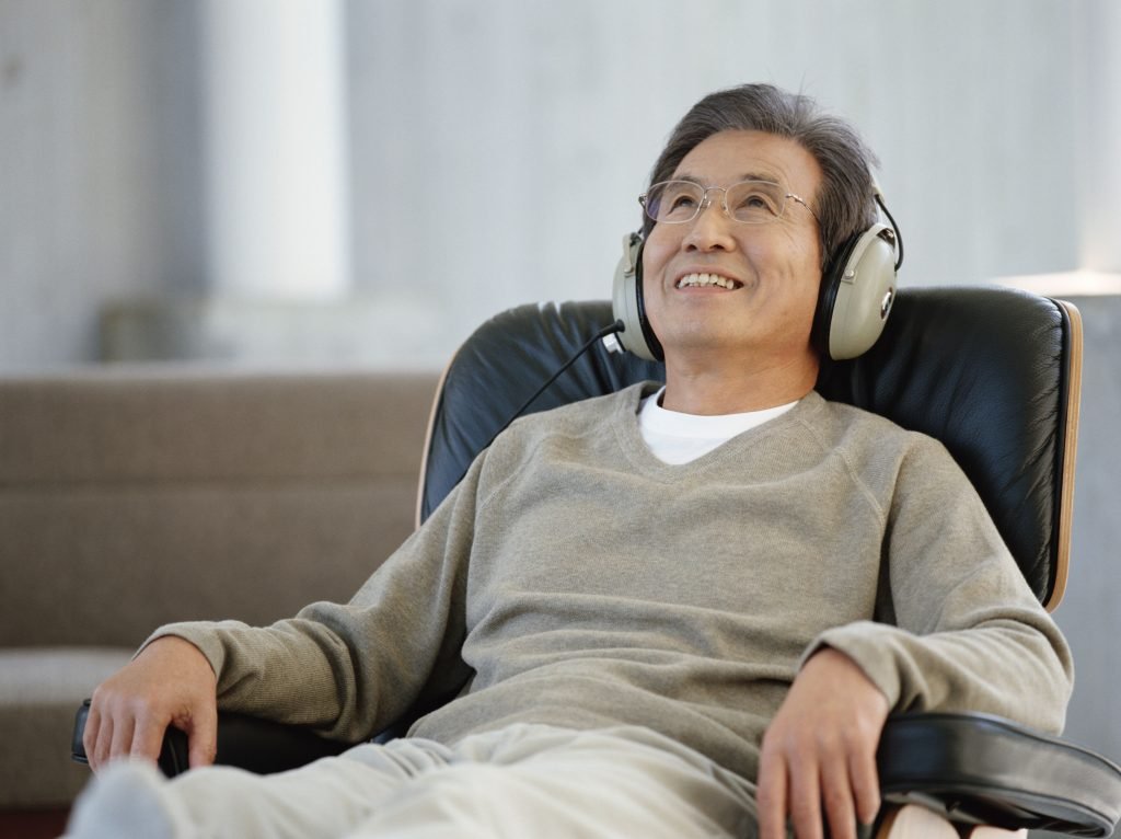 A man sits during an alcohol addiction research session while listening to a comedy show with headphones on.